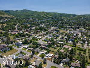 Aerial view of property and surrounding area featuring a mountain backdrop and nearby suburban area