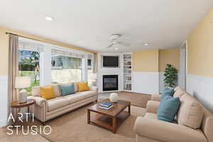 Carpeted living area featuring built in features, a ceiling fan, a wainscoted wall, a glass covered fireplace, and recessed lighting
