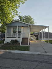 Manufactured / mobile home with driveway, an attached carport, and a porch