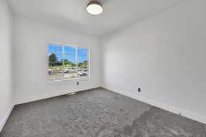 Empty room featuring dark carpet and baseboards