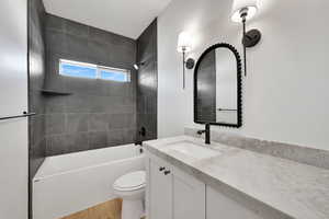 Bathroom with tub / shower combination, vanity, toilet, and wood finished floors