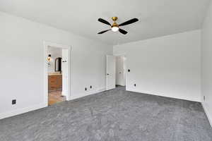Unfurnished bedroom with carpet, baseboards, ensuite bathroom, and a ceiling fan