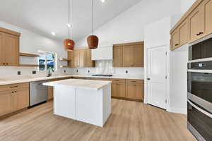 Kitchen with appliances with stainless steel finishes, open shelves, light countertops, high vaulted ceiling, and a sink