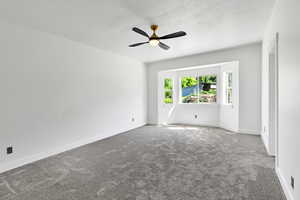 Carpeted empty room with a ceiling fan, a textured ceiling, and baseboards