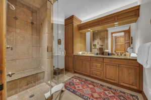 Bathroom with a stall shower, double vanity, and light tile patterned floors