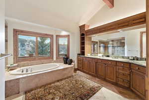 Bathroom featuring a stall shower, vanity, a garden tub, and lofted ceiling