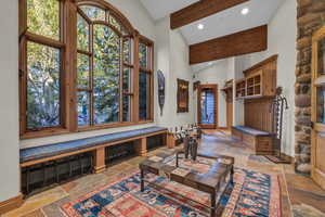 Living room featuring stone tile flooring, beam ceiling, high vaulted ceiling, and recessed lighting