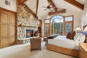 Bedroom with access to outside, a ceiling fan, lofted ceiling, light carpet, and a stone fireplace