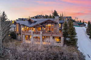 Back of house featuring a chimney, stone siding, and a wooden deck