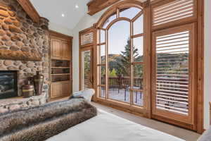 Entryway with vaulted ceiling, a stone fireplace, a mountain view, and recessed lighting