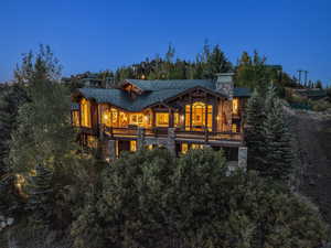 Back of house with a chimney, stone siding, covered porch, and log veneer siding