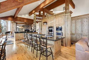 Kitchen with a breakfast bar area, light wood-style flooring, light wood finish cabinets, dark stone counters, and lofted ceiling