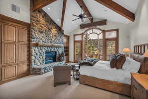 Bedroom with high vaulted ceiling, a stone fireplace, beam ceiling, light carpet, and recessed lighting