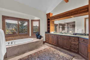 Full bathroom featuring vanity, a shower stall, a garden tub, and high vaulted ceiling