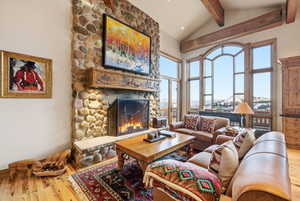 Living room featuring a stone fireplace, lofted ceiling, a mountain view, and light wood-type flooring