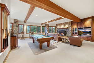 Game room featuring light colored carpet, pool table, a stone fireplace, beam ceiling, and recessed lighting