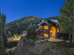 Back of house with a forest view, a mountain view, a chimney, and stairs