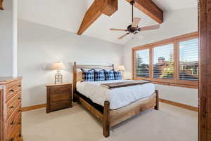Bedroom with vaulted ceiling with beams, light colored carpet, and a ceiling fan