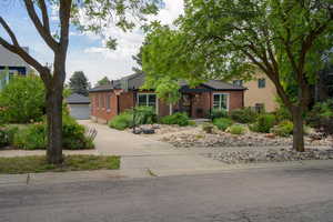 Ranch-style house featuring brick siding, a detached garage, an outbuilding, and a tile roof