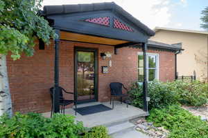 Doorway to property with covered porch and brick siding