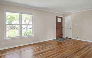 Foyer entrance featuring wood finished floors, baseboards, and ornamental molding