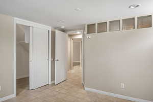 Empty room featuring baseboards, light tile patterned floors, and recessed lighting