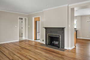Unfurnished living room featuring light wood-type flooring, ornamental molding, baseboards, a tile fireplace, and recessed lighting