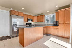 Kitchen featuring appliances with stainless steel finishes, a center island, recessed lighting, a sink, and light tile patterned floors