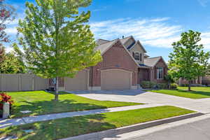 View of front of home with brick siding, a garage, and driveway