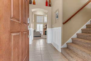 Foyer entrance with stairs, light tile patterned flooring, a glass covered fireplace, and a high ceiling