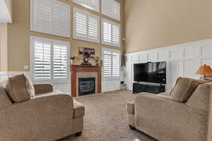 Living room featuring a tile fireplace, carpet flooring, and a high ceiling