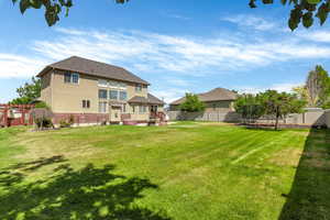 Back of house featuring a trampoline, stucco siding, brick siding, a gate, and roof with shingles