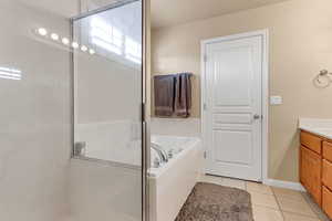 Bathroom featuring vanity, tile patterned floors, a garden tub, a shower with shower door, and baseboards
