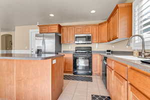 Kitchen featuring stainless steel appliances, a sink, light tile patterned floors, arched walkways, and recessed lighting