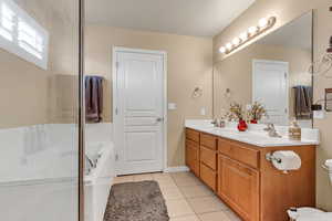Bathroom featuring tile patterned floors, double vanity, toilet, a bathtub, and a shower