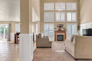 Living area featuring a high ceiling, a tile fireplace, tile patterned floors, wainscoting, and a textured ceiling