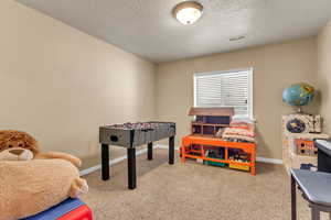 Playroom with carpet floors, a textured ceiling, and baseboards