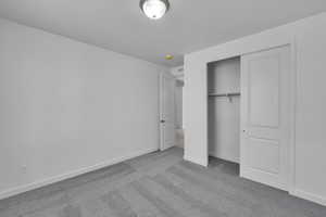 Unfurnished bedroom with carpet floors, baseboards, and a closet