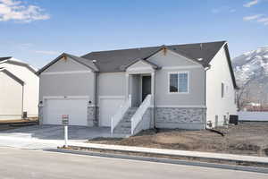 Ranch-style home featuring stone siding, a mountain view, concrete driveway, an attached garage, and central AC unit