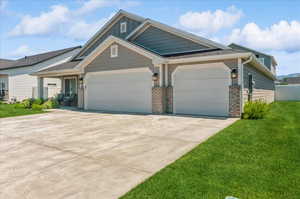Craftsman-style house with an attached garage, a front yard, driveway, brick siding, and board and batten siding