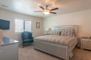 Bedroom featuring light colored carpet, a textured ceiling, and a ceiling fan