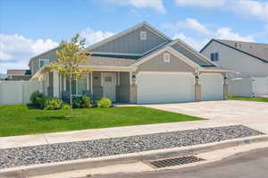 Craftsman-style house featuring board and batten siding, a garage, driveway, brick siding, and a porch