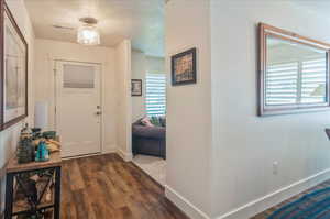 Entryway with a textured ceiling, dark wood-style floors, and baseboards