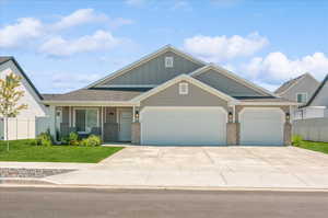 Craftsman inspired home featuring brick siding, an attached garage, board and batten siding, and driveway