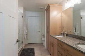 Full bath with double vanity, a stall shower, and toilet