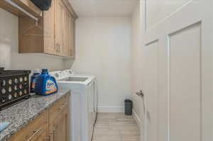 Laundry room with washer and clothes dryer, baseboards, light wood-type flooring, and cabinet space