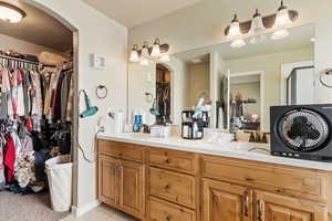 Bathroom featuring double vanity, a spacious closet, and tile patterned flooring