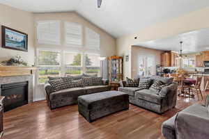 Living area with a premium fireplace, light wood-type flooring, and high vaulted ceiling