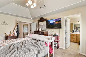 Bedroom featuring light carpet, light tile patterned floors, lofted ceiling, and ensuite bathroom