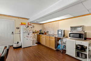 Kitchen featuring freestanding refrigerator, stainless steel microwave, a sink, and dark wood-type flooring